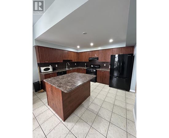 A kitchen with a black refrigerator and brown cabinets.