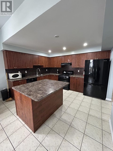 A kitchen with a black refrigerator and brown cabinets.