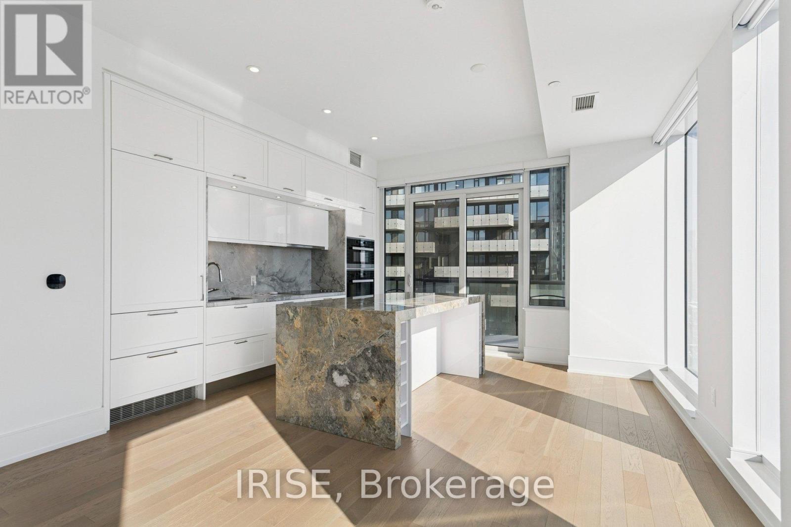 A modern kitchen with white cabinets and a stone island.