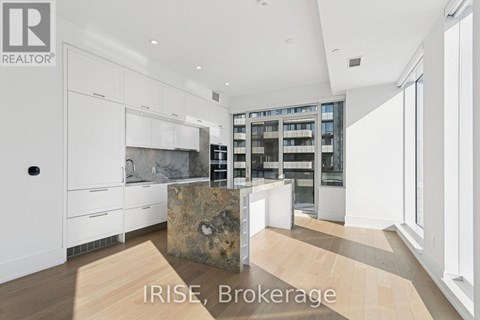 A modern kitchen with white cabinets and a stone island.
