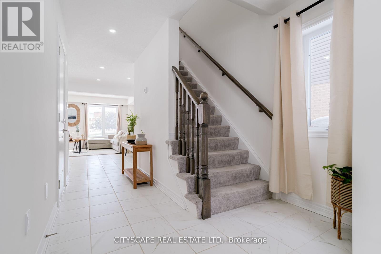 A spacious hallway with a staircase and a table with a plant on it.
