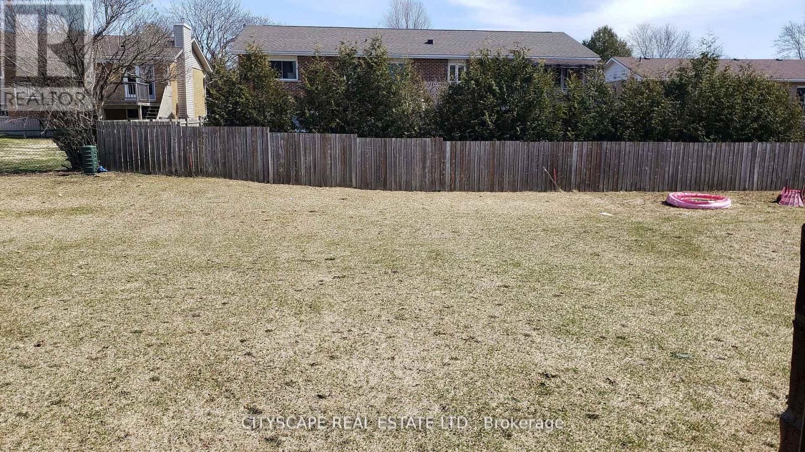 A backyard with a wooden fence and a grassy area.