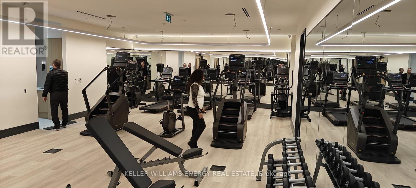 A gym with a variety of equipment and people working out.