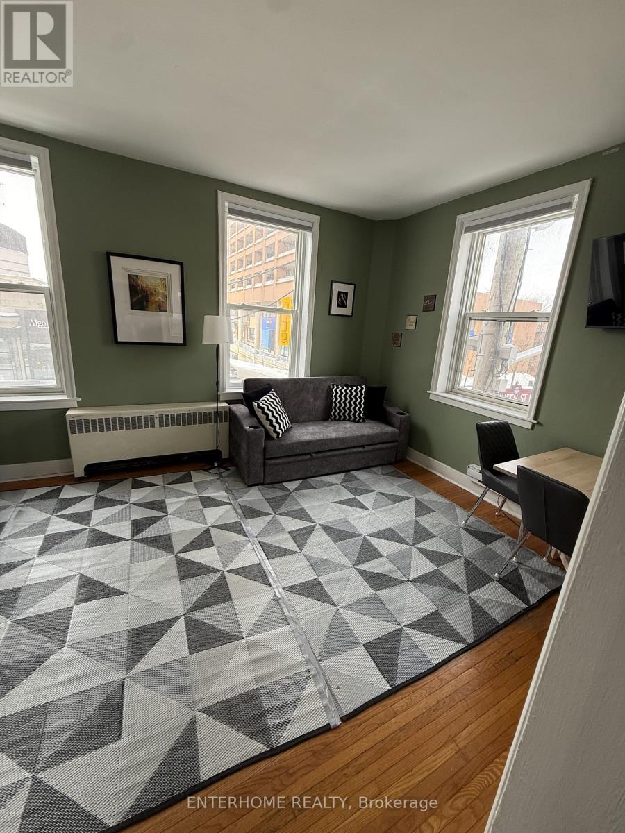 A living room with a grey sofa and a rug with a geometric pattern.