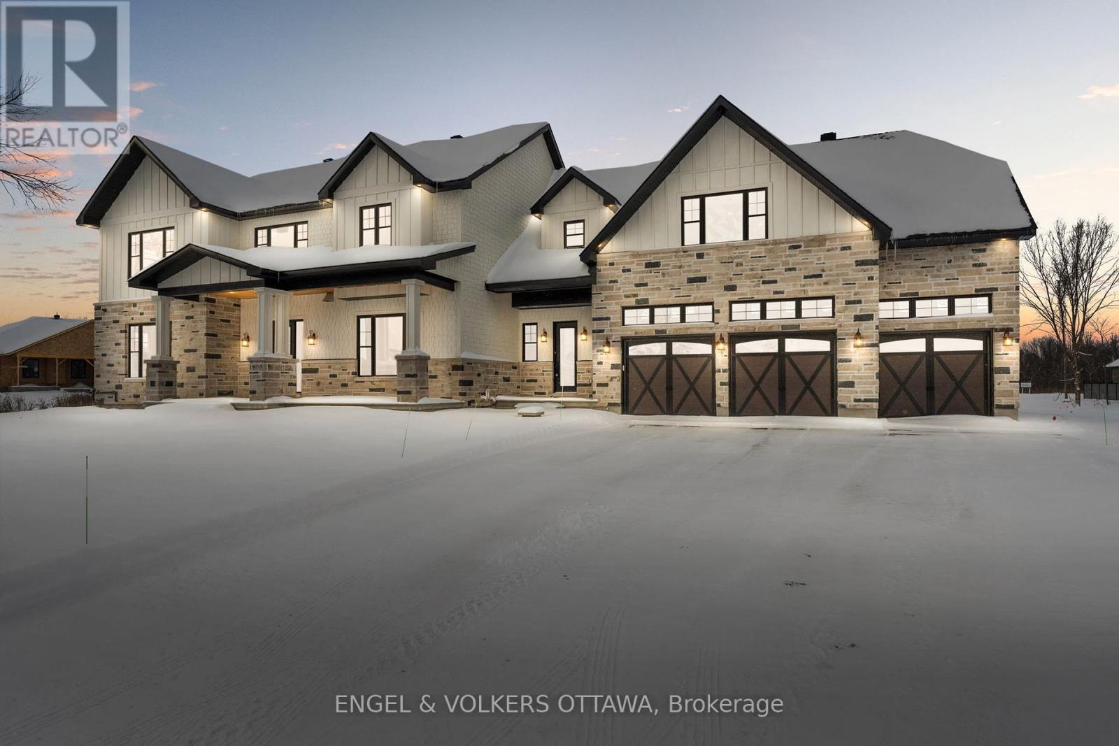 A large, modern house with a stone facade and multiple garages is the focus of this image.
