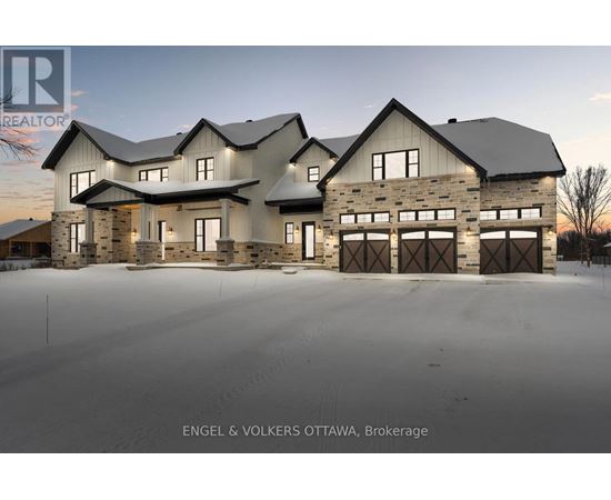 A large, modern house with a stone facade and multiple garages is the focus of this image.
