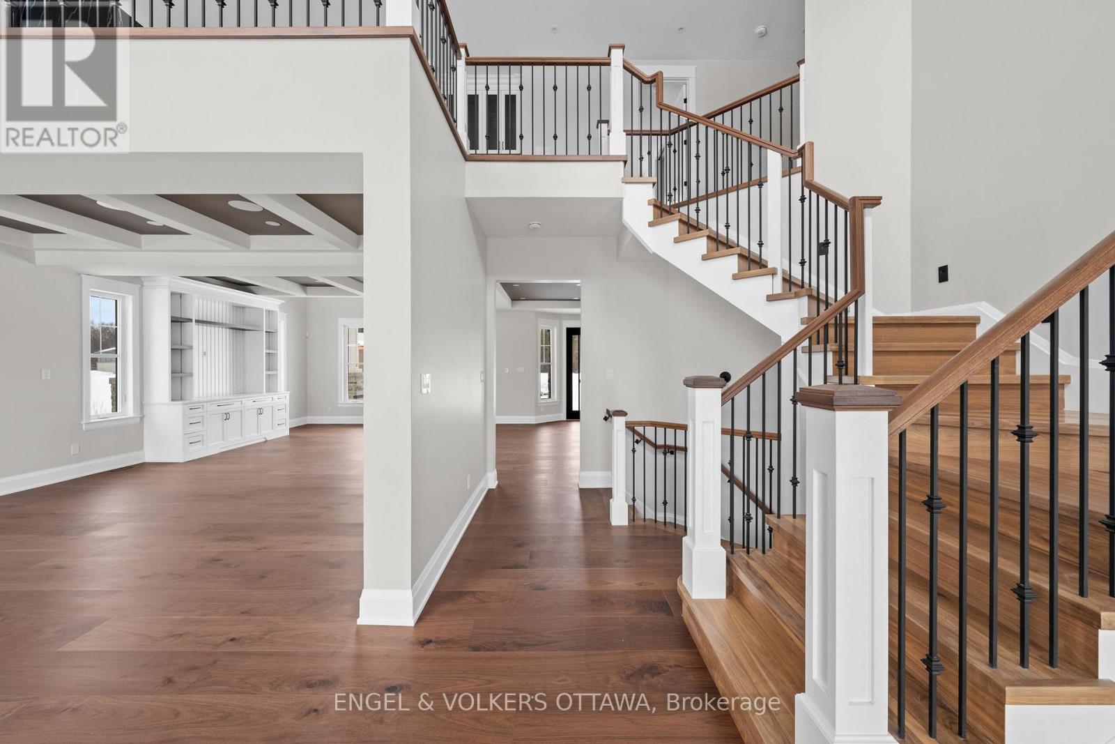 A spacious home interior with a staircase and a brokerage logo.