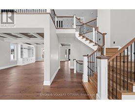 A spacious home interior with a staircase and a brokerage logo.