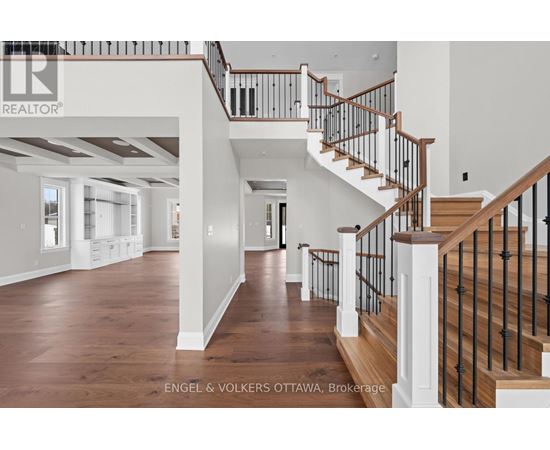 A spacious home interior with a staircase and a brokerage logo.
