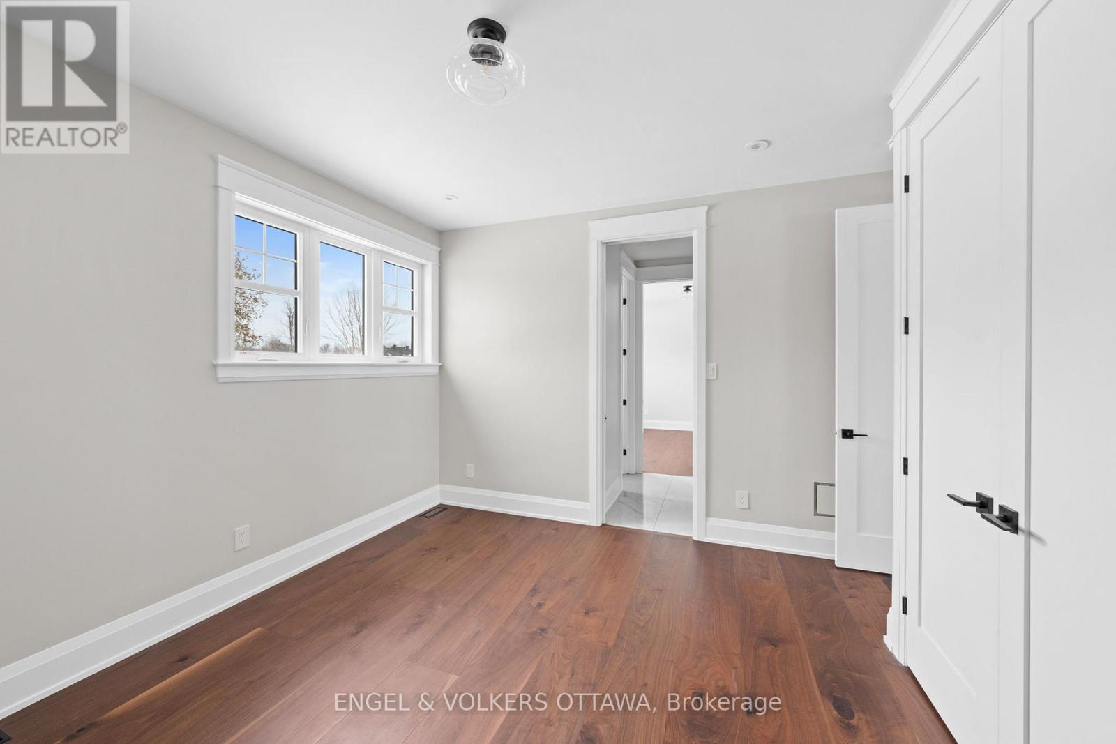 A room with a white door and a window with a view of trees.