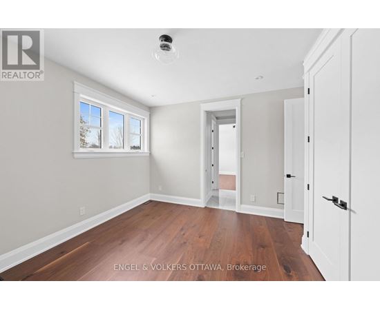 A room with a white door and a window with a view of trees.