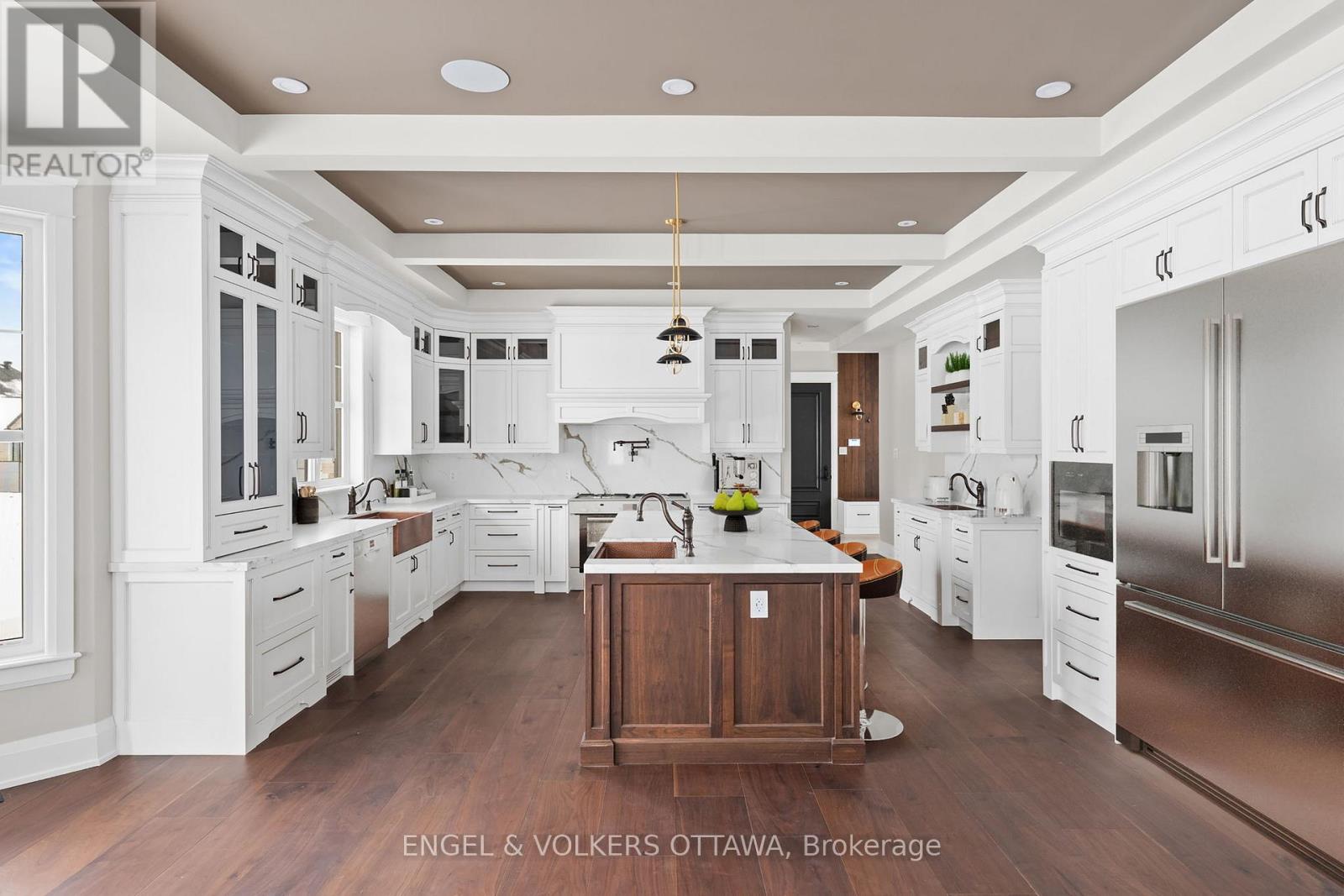 A large, modern kitchen with white cabinets and a wooden island.