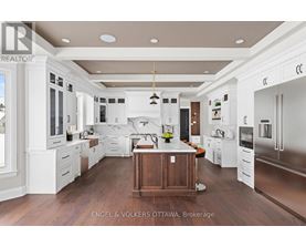 A large, modern kitchen with white cabinets and a wooden island.