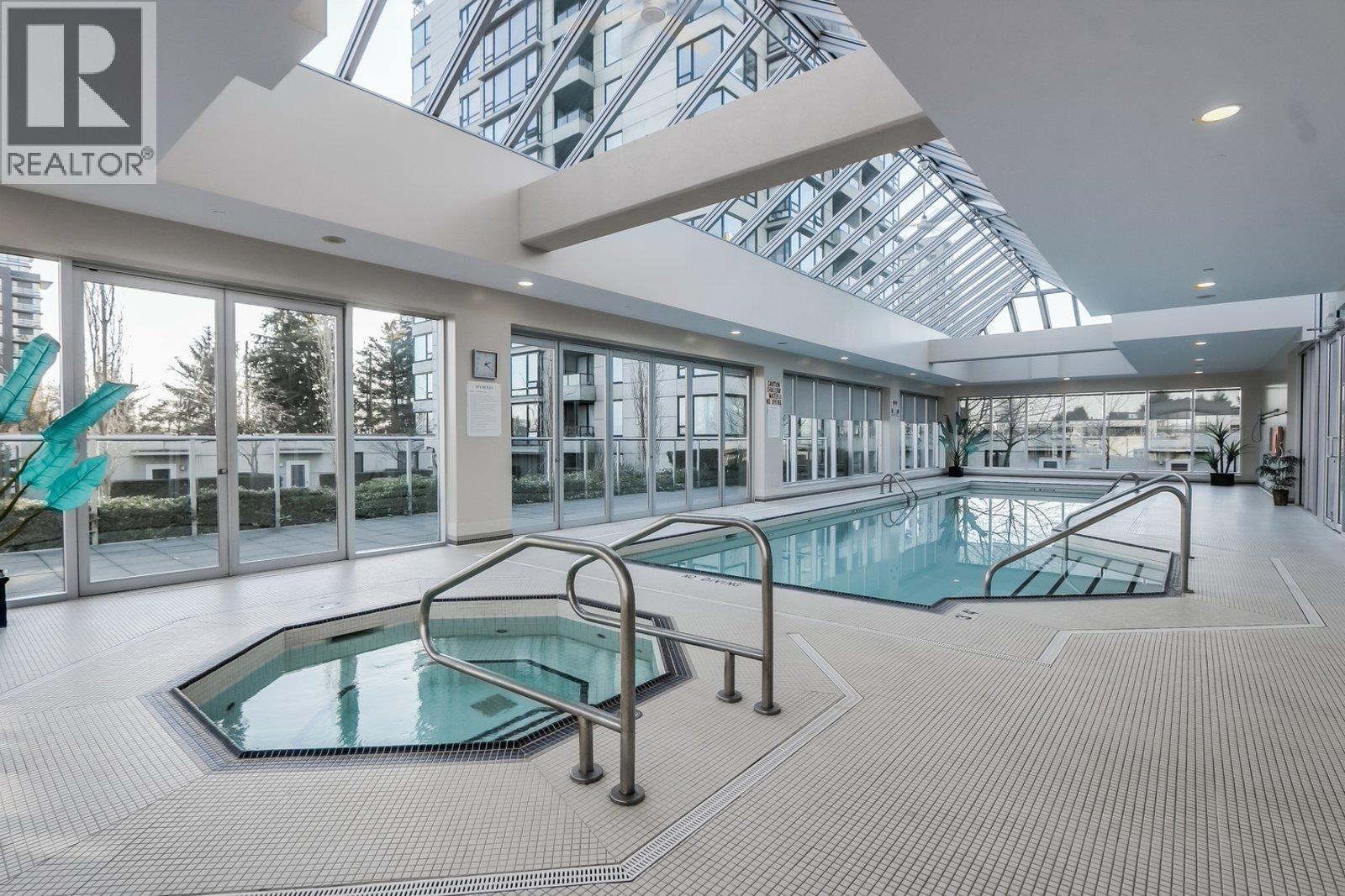 A large indoor swimming pool with a glass ceiling.