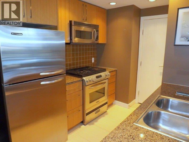 A kitchen with a stainless steel refrigerator, oven, and microwave.