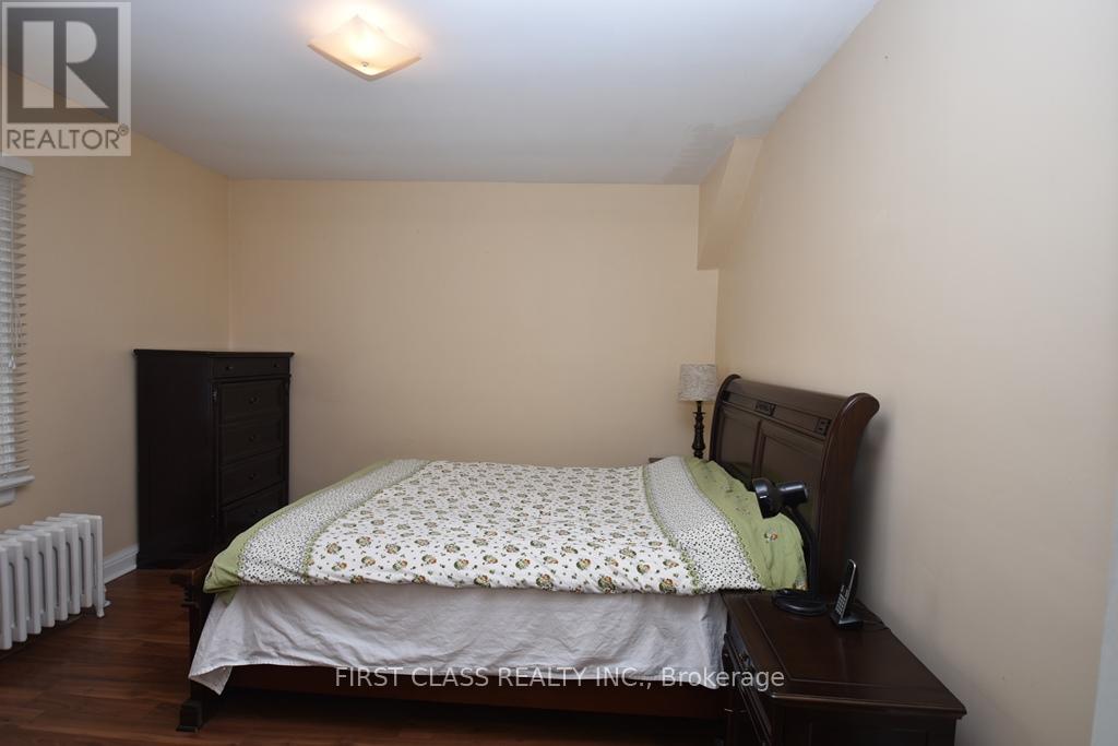 A bedroom with a bed, nightstand, and a radiator.