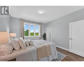 A bedroom with a large bed and a window overlooking a green area.