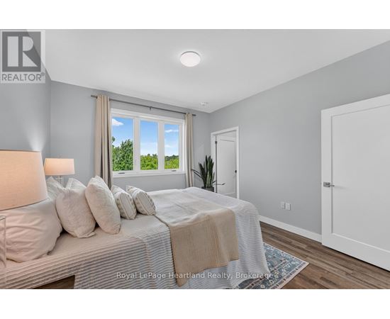 A bedroom with a large bed and a window overlooking a green area.