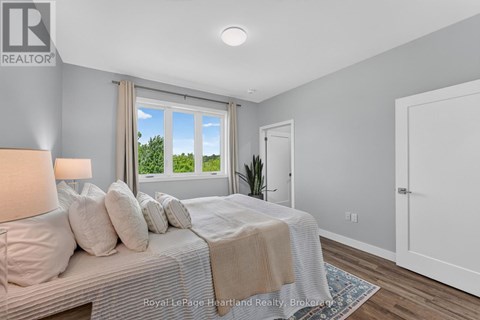 A bedroom with a large bed and a window overlooking a green area.