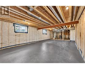 A spacious, unfinished room with exposed ceiling beams and a window.