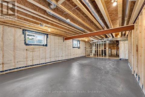 A spacious, unfinished room with exposed ceiling beams and a window.