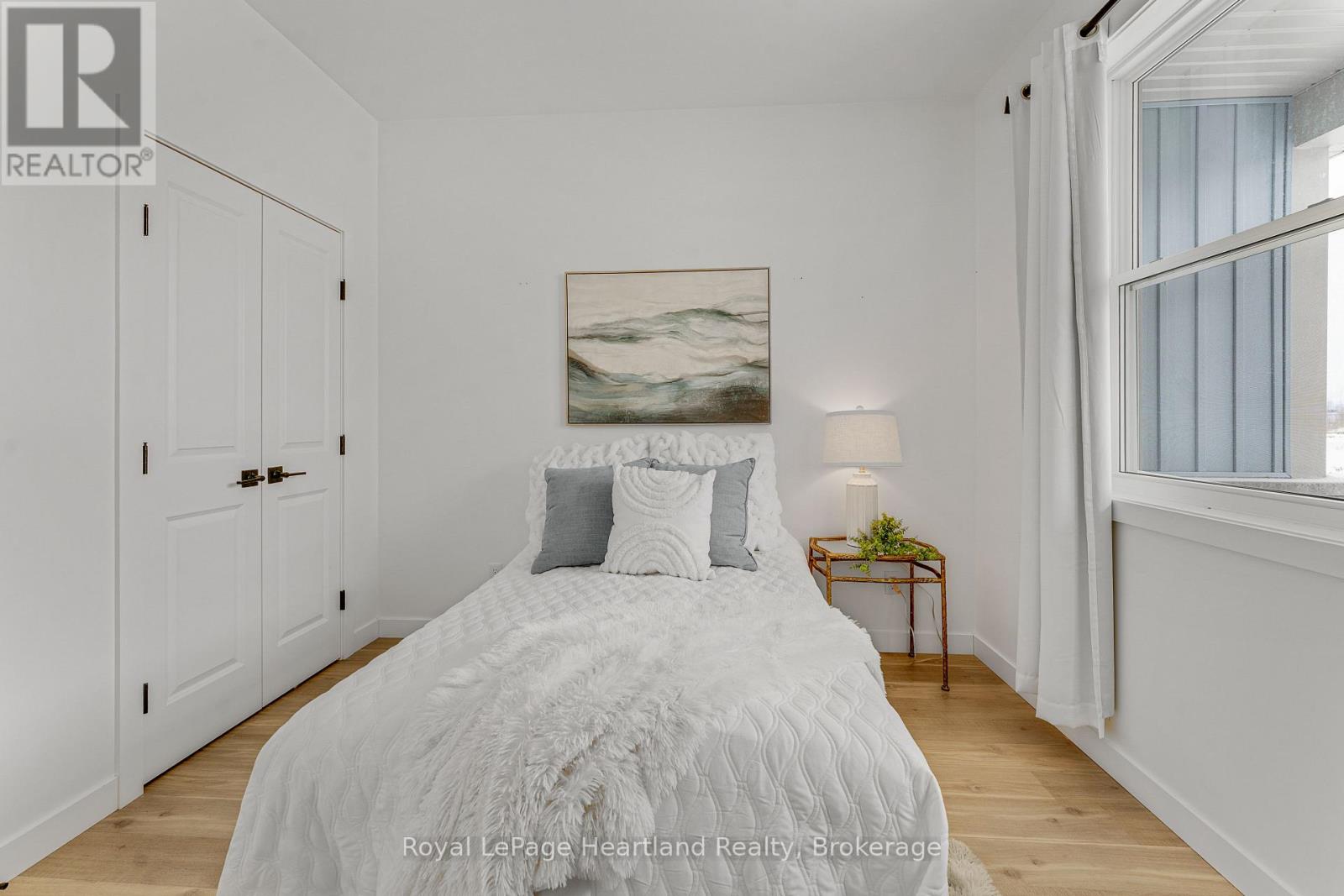 A bedroom with a large bed and a painting on the wall.