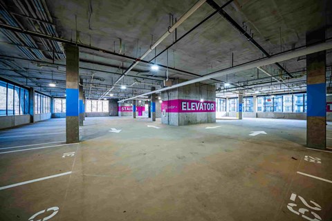 A spacious parking garage with a sign that reads "ELEVATOR" in the background.