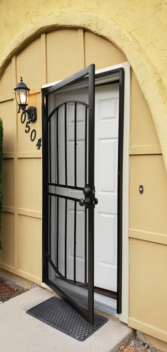 A black gate with a white door is closed.