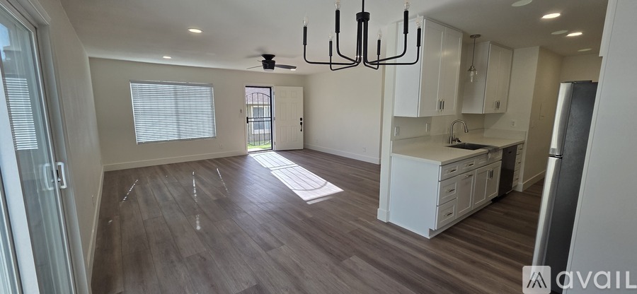 A large, empty room with wood flooring and a chandelier.