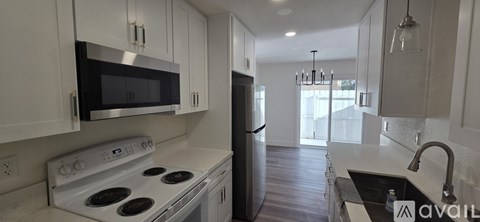 A kitchen with white cabinets and a stove top oven.
