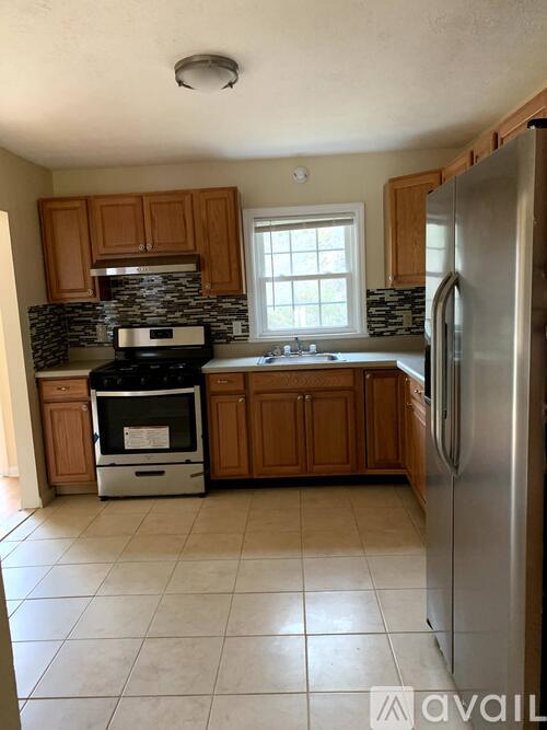 A kitchen with wooden cabinets and a stainless steel refrigerator.