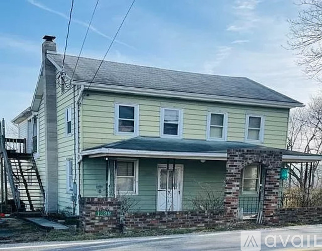 A two-story house with a greenish exterior and a brick chimney.