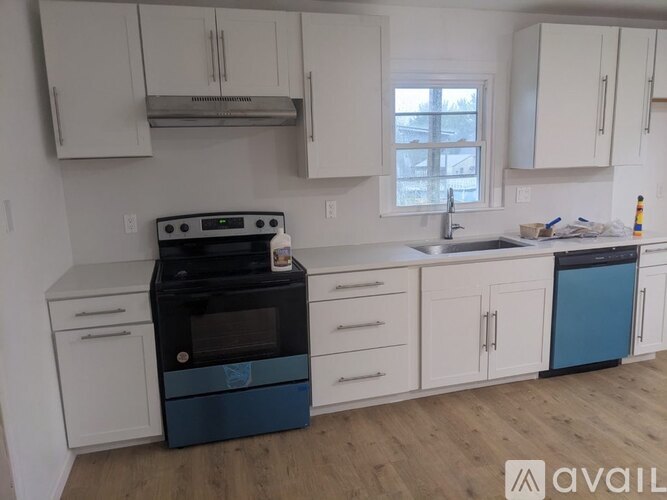 A kitchen with white cabinets and a black and blue dishwasher.