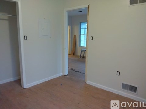 A room with a white wall and a doorway leading to another room.