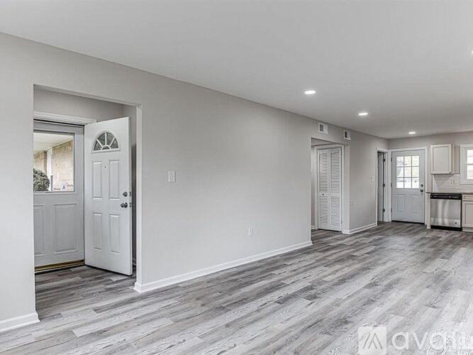 A spacious room with a white door and a grey floor.