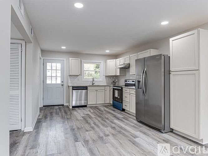 A kitchen with white cabinets and a grey floor.