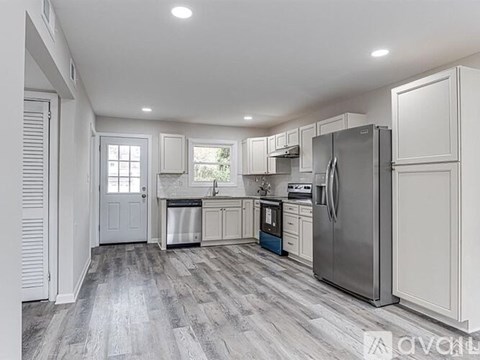 A kitchen with white cabinets and a grey floor.