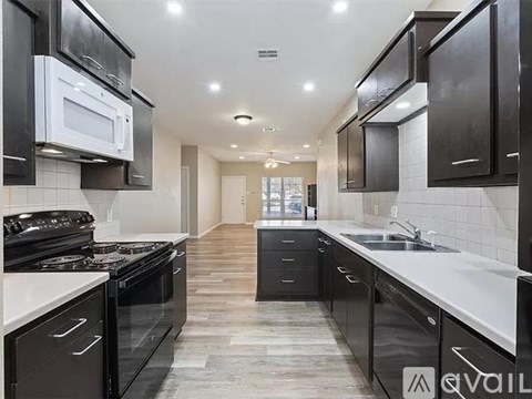 A modern kitchen with black cabinets and white countertops.