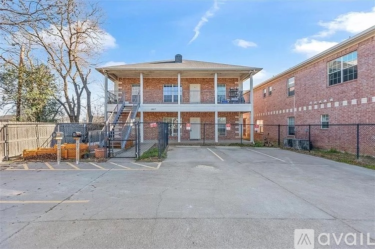 A building with a balcony and a parking lot in front.