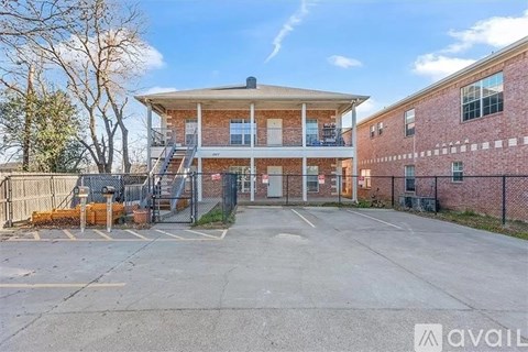 A building with a balcony and a parking lot in front.
