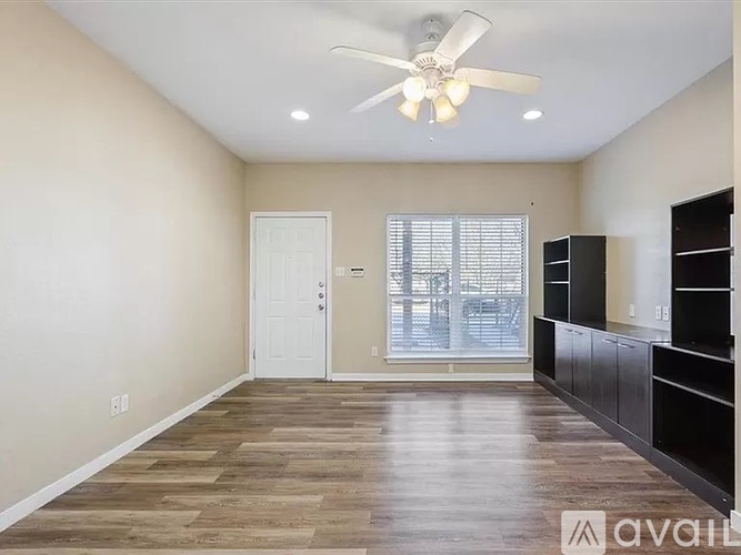 A spacious room with a ceiling fan and wooden flooring.