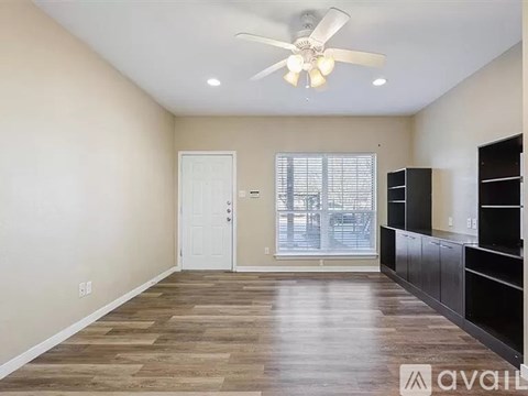 A spacious room with a ceiling fan and wooden flooring.