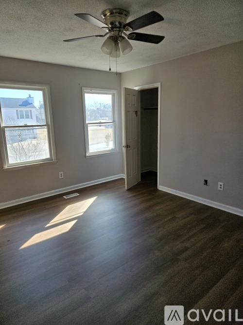 A room with a ceiling fan and two windows.