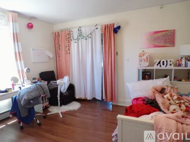 A messy bedroom with a bed, chair, and clothes scattered about.