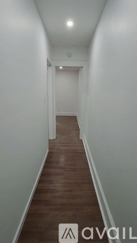 A long hallway with wood floors and white walls.