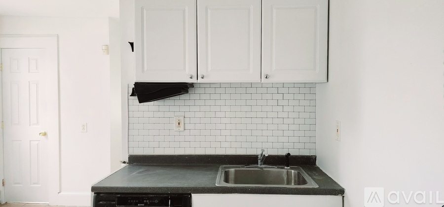 A kitchen with white cabinets and a black countertop.