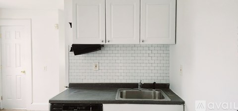 A kitchen with white cabinets and a black countertop.