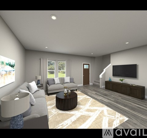 A modern living room with a grey sofa, a coffee table, and a flat-screen TV mounted on the wall.