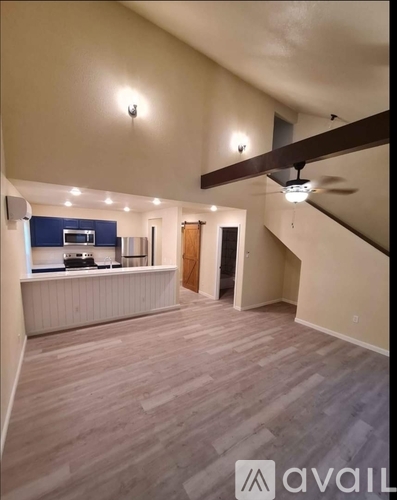 A spacious room with a staircase and a kitchen area.