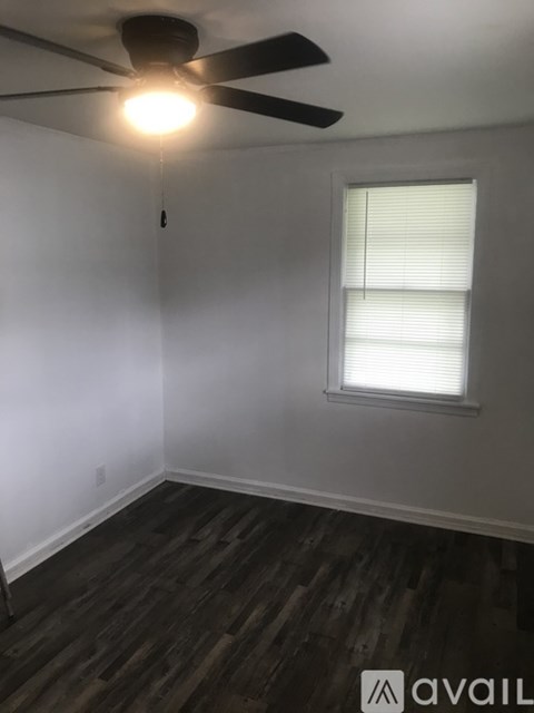 A room with a ceiling fan and a window with blinds.